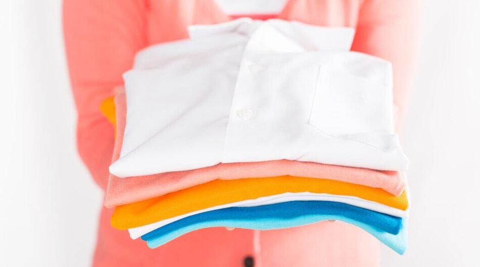 midsection-woman-holding-folded-shirts-against-white-background_1048944-24916484