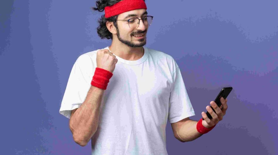 compressed_smiling-young-sporty-man-wearing-headband-with-wristband-holding-looking-phone-showing-yes-gesture-1