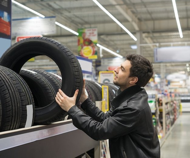 male-customer-choosing-new-tires-car-hypermarket-he-is-taking-tire-from-shelf_461973-881