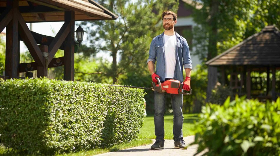 happy-bearded-gardener-standing-carrying-modern-hand-hedge-trimmer-park-low-angle-view-2_11zon