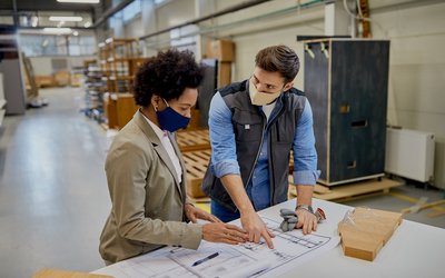 african-american-businesswoman-carpenter-wearing-face-masks-while-analyzing-design-plans-production-facility-1